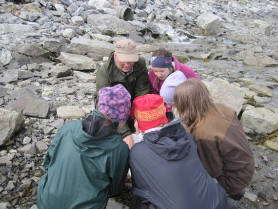 Elever samlet rundt en lærer i fjærsteinene.