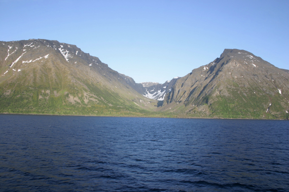 Foto av en dal mellom to fjell ved sjøen.