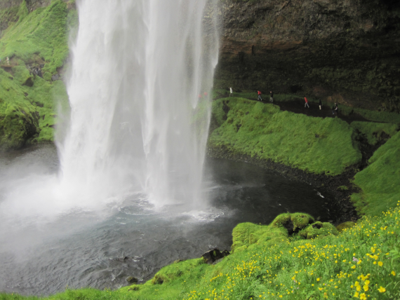 Bilde av folk som går bak en stor foss.