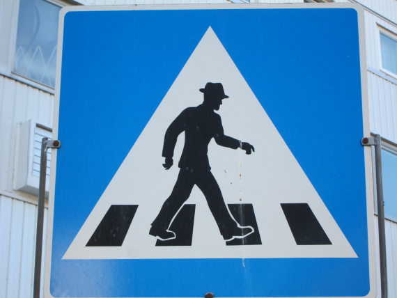Nærbilde av skilt, en mann som går over veien.