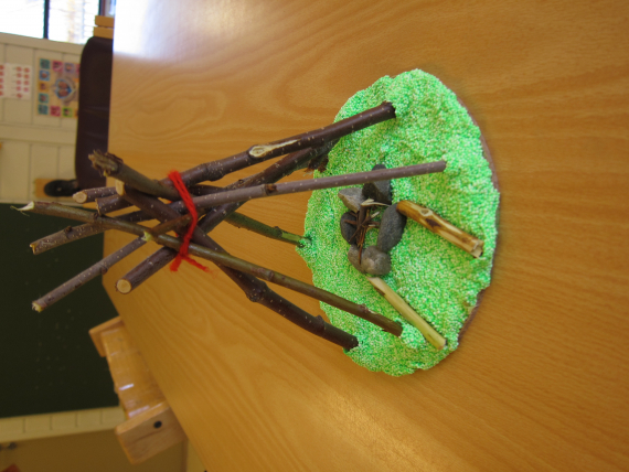 Liten lavvo laget av trepinner og garn, og med ildsted laget av småstein.