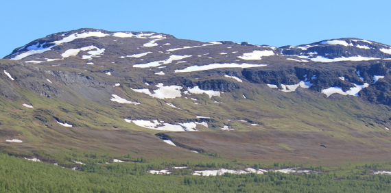 Foto av et fjell med sneflekker.