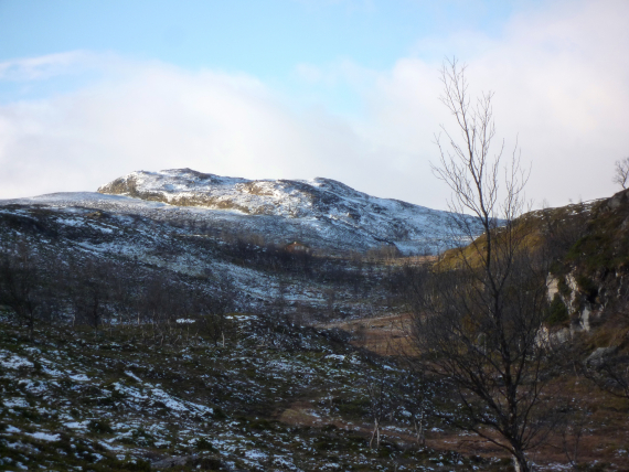 Foto av et fjell med litt sne på om høsten.