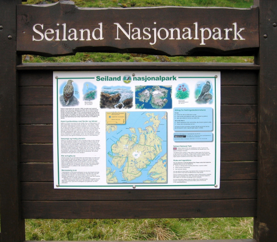 Foto av et skilt der det står Seiland Nasjonalpark, med plakat av kart og informasjon