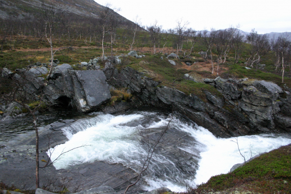 Foto av en liten foss i høstlandskap.