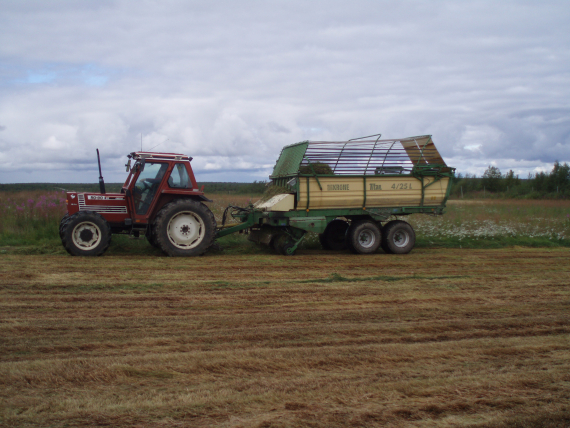 Bilde av en traktor som høster inn gress.