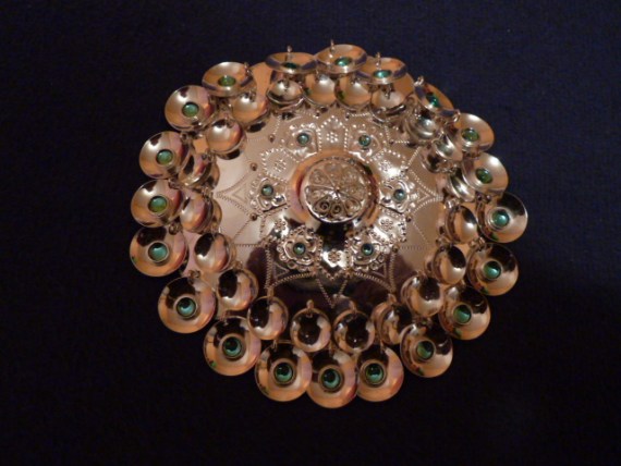 Foto av en stor sølvsølje med grønne stener.