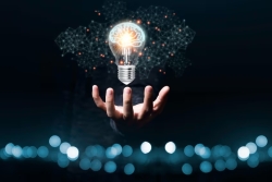 hånd som holdes under en lysende lyspære